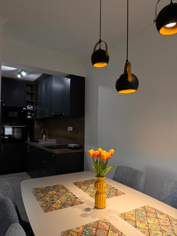 a dining room table with a yellow vase with orange flowers at Venima City Center Apartment in Tivat
