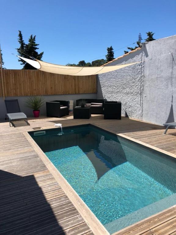 une piscine avec une terrasse en bois et un patio dans l'établissement Maison avec piscine privative chauffée, à Sanary-sur-Mer