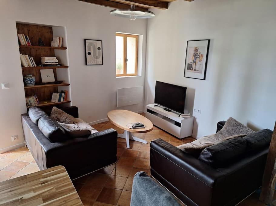 een woonkamer met 2 banken en een televisie bij Ruelle maison ancienne in Saint-Romain