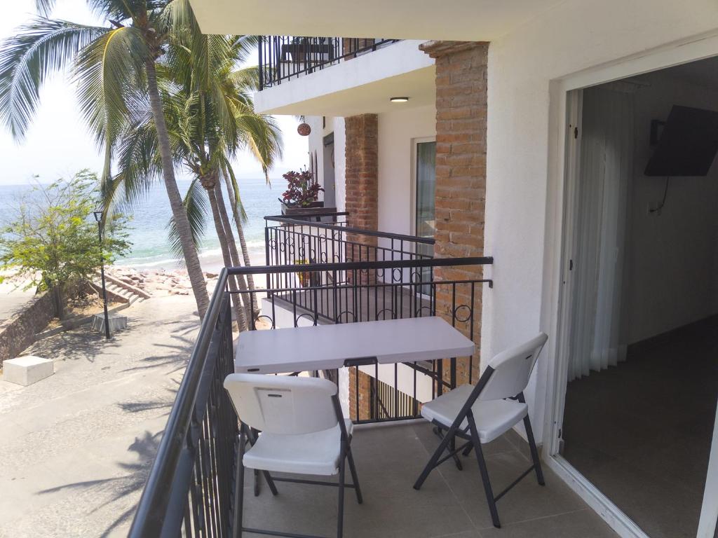 a balcony with a table and chairs and the beach at Departamento Concha de Mar in Puerto Vallarta