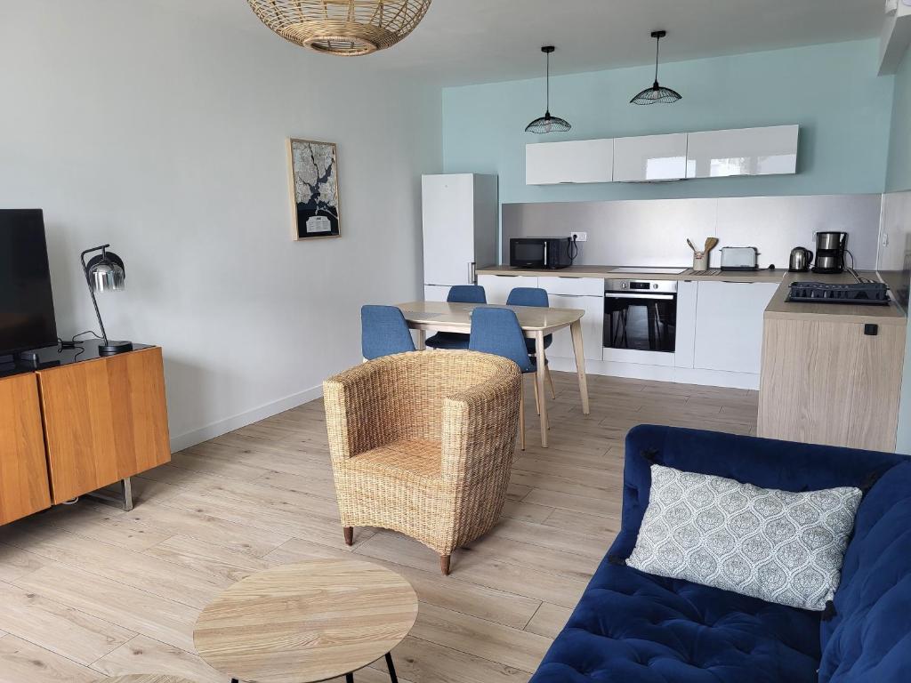 un salon avec un canapé bleu et une cuisine dans l'établissement Plein pied de la petite mer, à Riantec