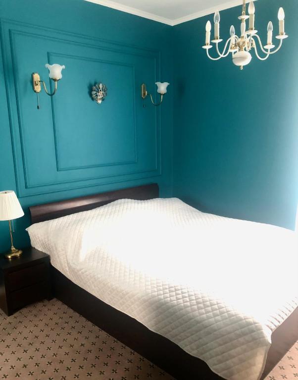 a blue bedroom with a white bed and a chandelier at Stara Praga in Warsaw