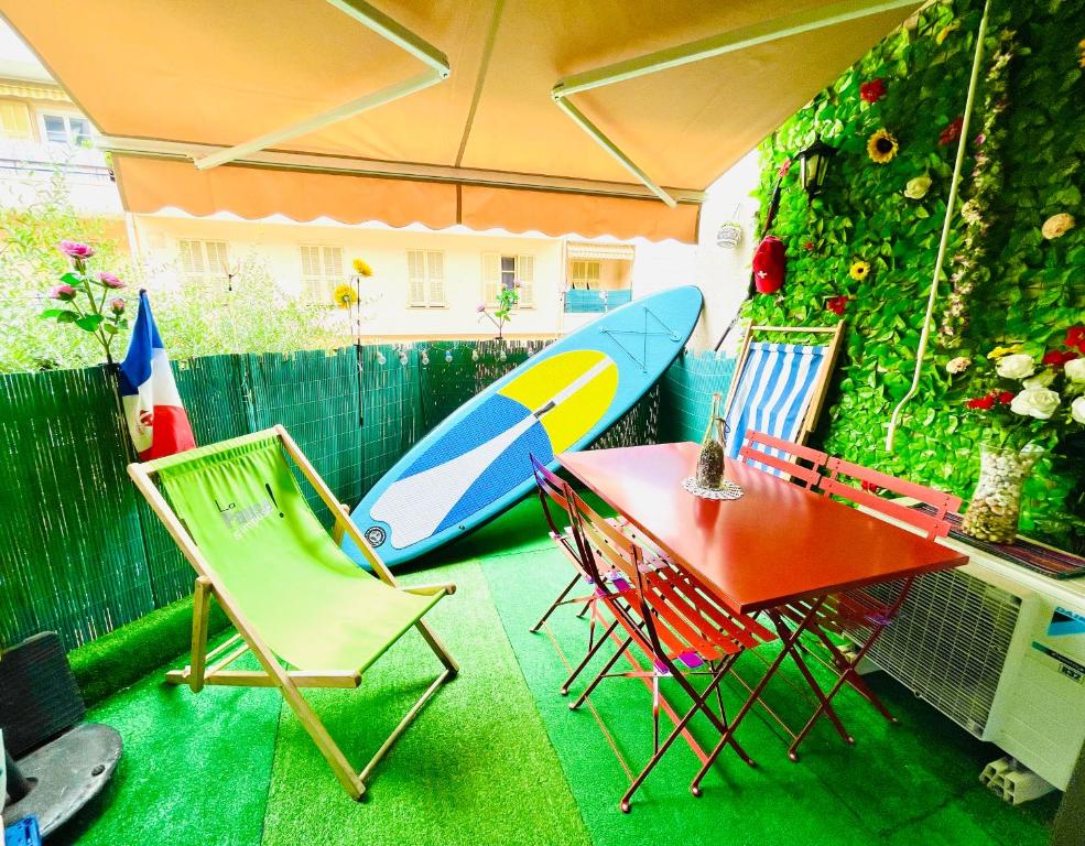 une terrasse avec une table, des chaises et une planche de surf dans l'établissement studio city center beach side free paddle beautiful terrace, à Nice