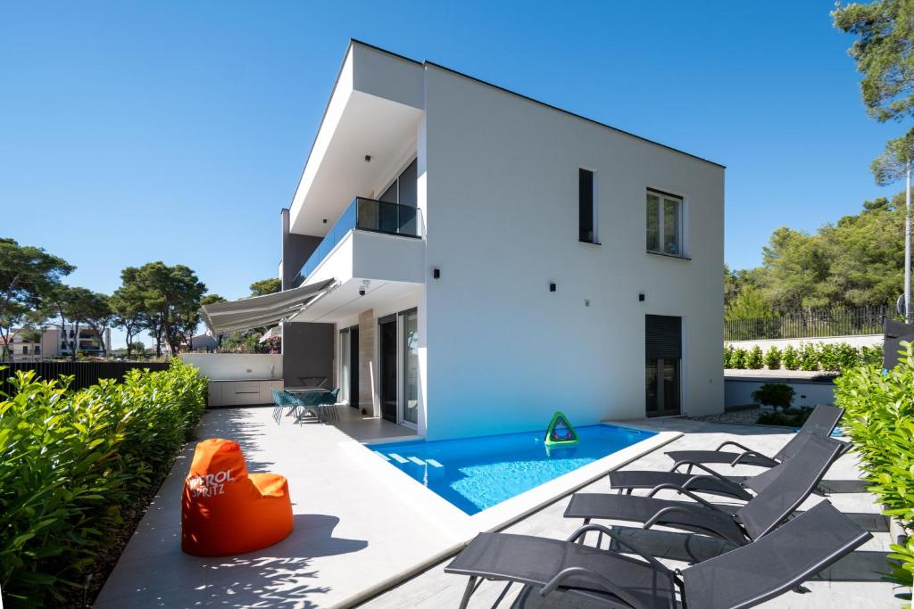 a white house with a swimming pool and chairs at Family friendly house with a swimming pool Bibinje, Zadar - 23363 in Bibinje