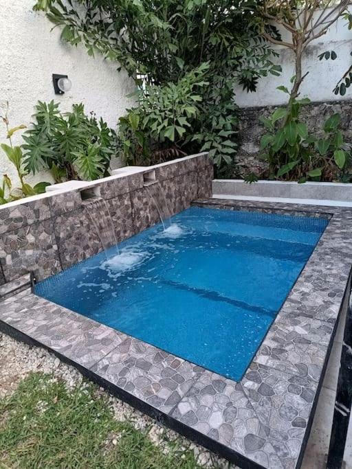 a swimming pool with blue water in front of a house at Cozy House with Pool and AC Casa Armando in Cozumel