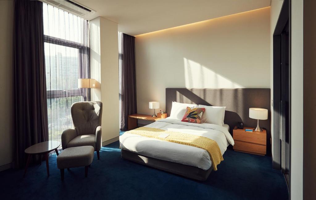 a bedroom with a bed and a chair and a window at La Casa Hotel Seoul in Seoul