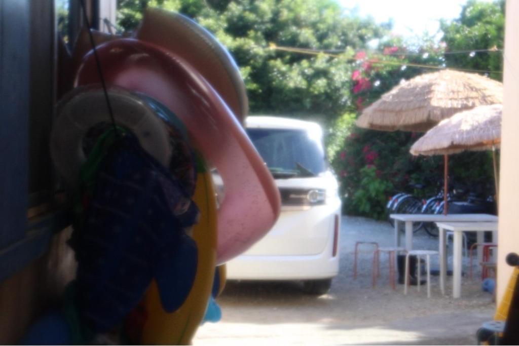 a white van parked next to a patio with tables and umbrellas at やどバンブー in Hateruma