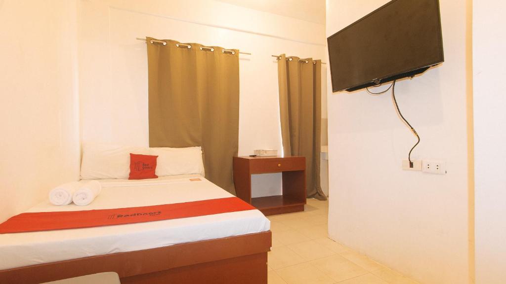 a small bedroom with a bed and a flat screen tv at RedDoorz @ The Central Inn Boracay Island in Boracay