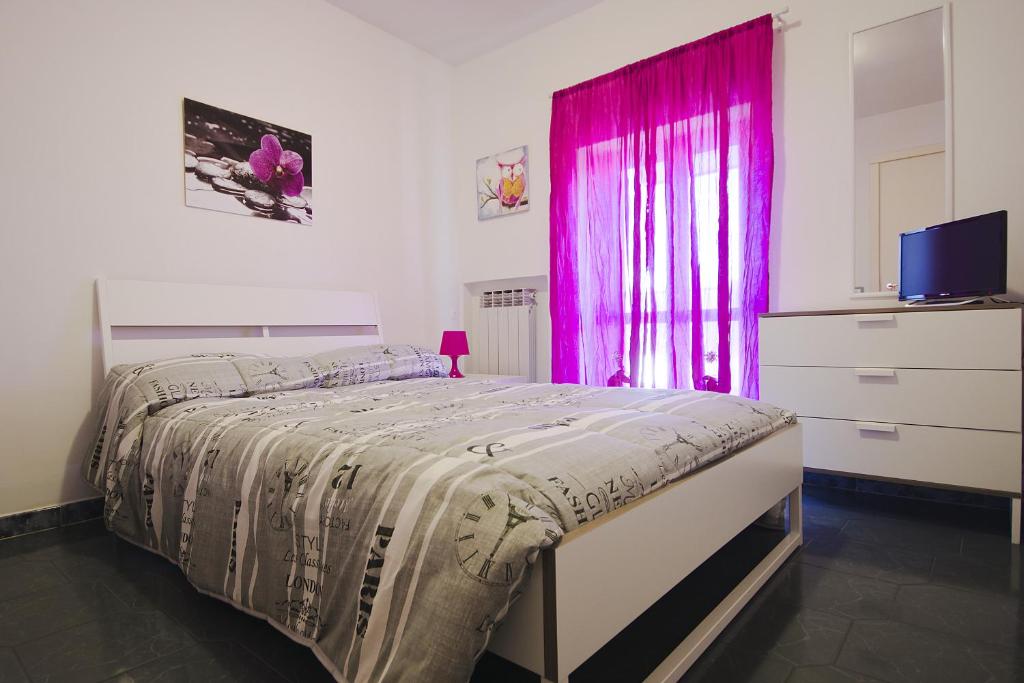 1 dormitorio con cama y ventana rosa en L'Attico, en Rende