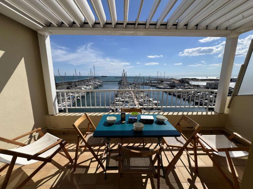 d'un balcon avec une table bleue et des chaises ainsi qu'un port de plaisance. dans l'établissement Studio-Cabine 23m², Clim, Parking, Lave-Linge, Cap d'Agde - FR-1-702-67, au Cap d'Agde
