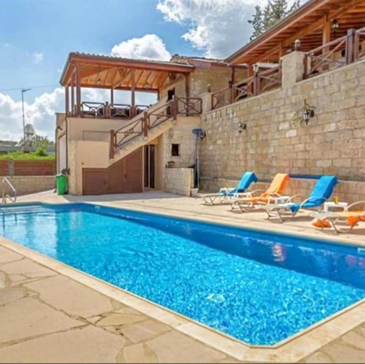 a swimming pool with chairs and a house at Villa Elizabeth in Limassol