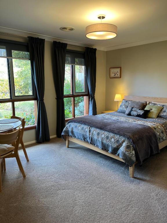 a bedroom with a bed and a table and windows at The Red Letterbox in Blackheath