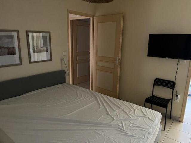 - une chambre avec un lit, une télévision et une chaise dans l'établissement Maison familiale à Domino, à Saint-Georges-dʼOléron