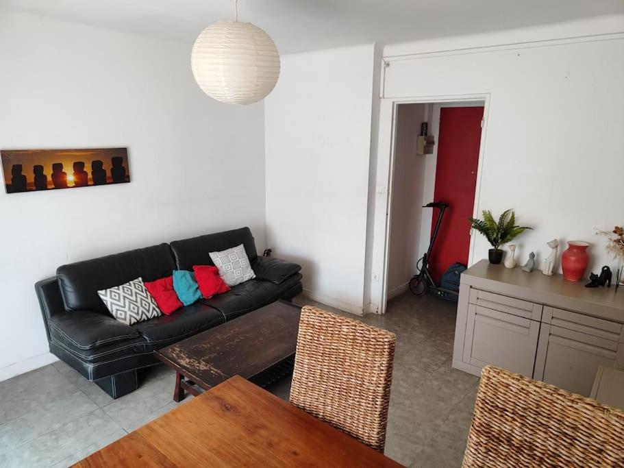un salon avec un canapé noir et une table dans l'établissement Appart 3 chambres 5 min centre, à Montpellier