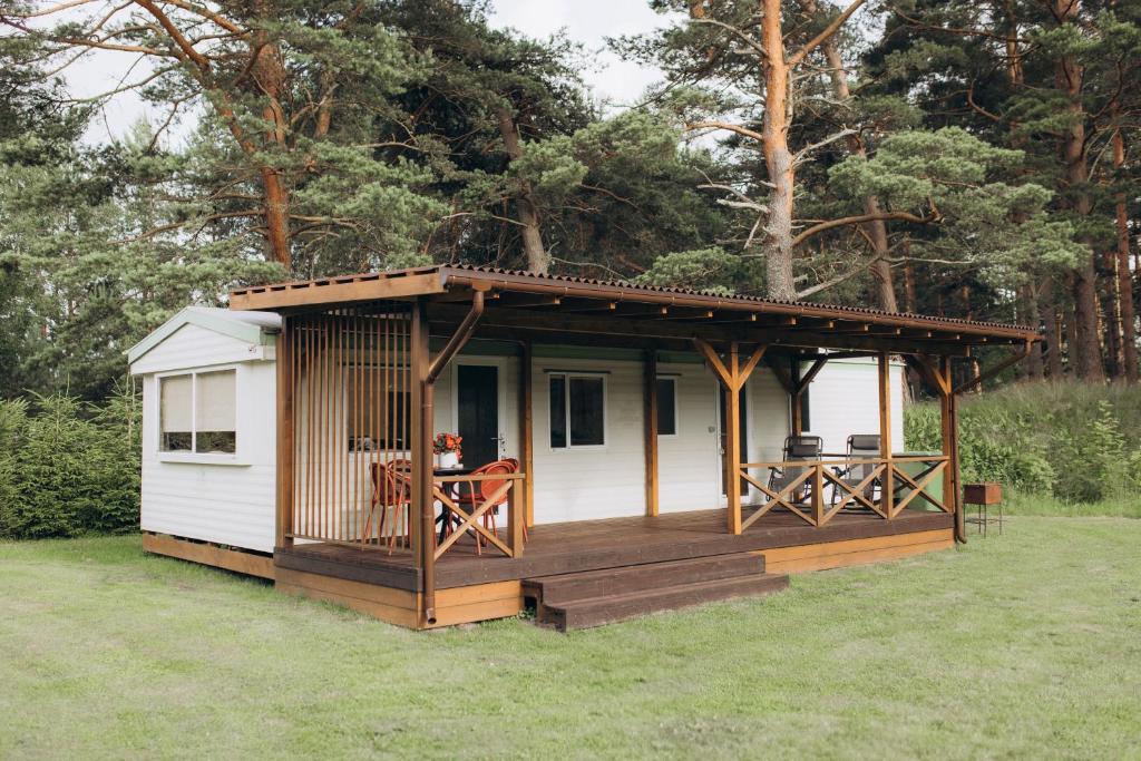 a small cabin with a deck in the grass at Atvases in Pērkone