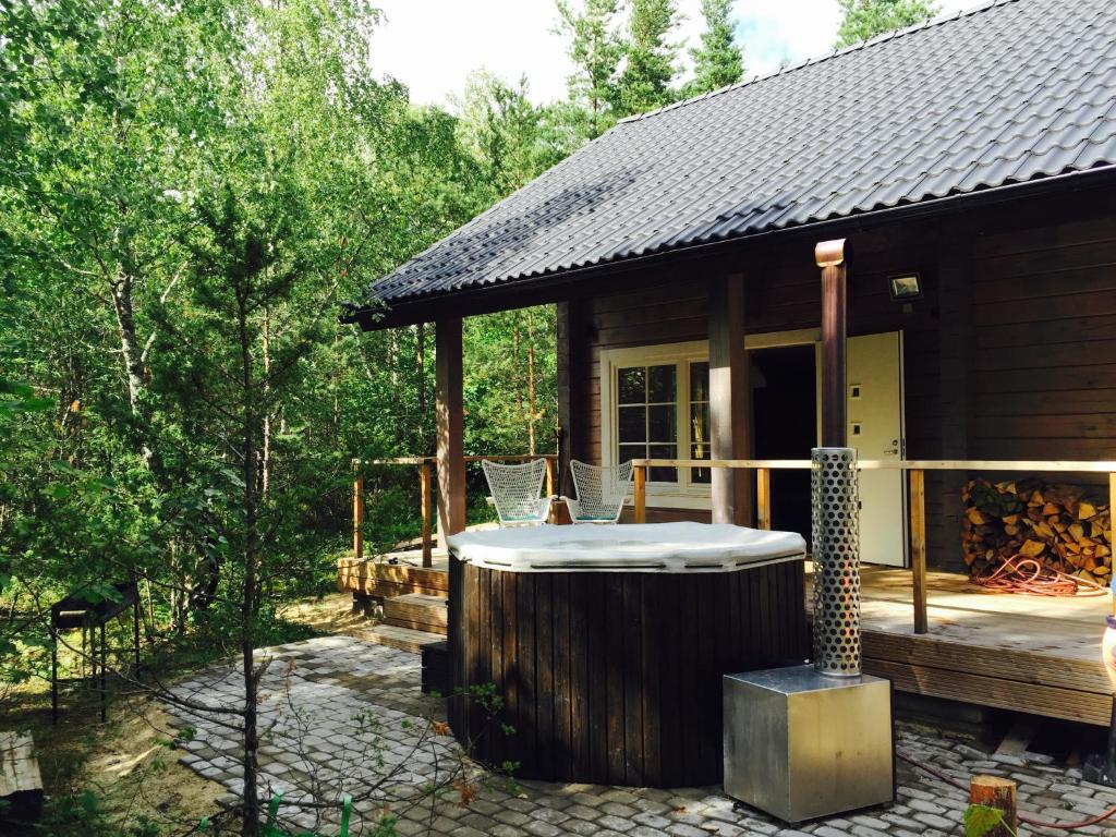 une cabane en rondins avec un bain à remous sur le pont dans l'établissement Hapsal Forest Cabin, à Haapsalu