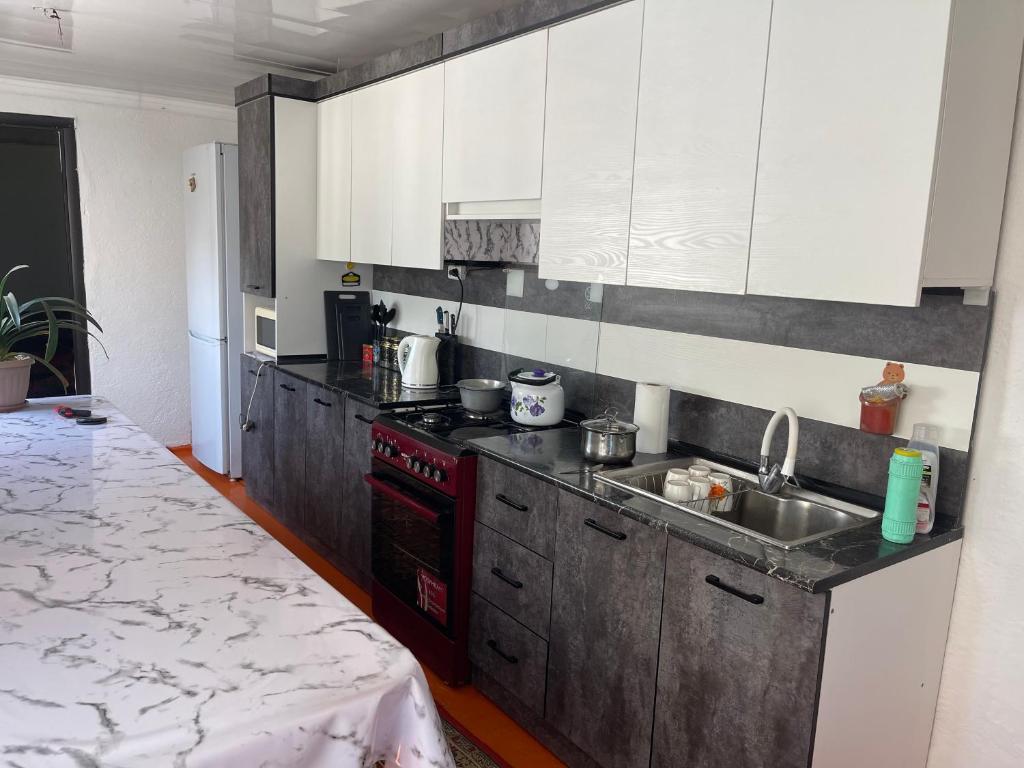 a kitchen with white cabinets and a red stove top oven at magic home in Boz-Beshik