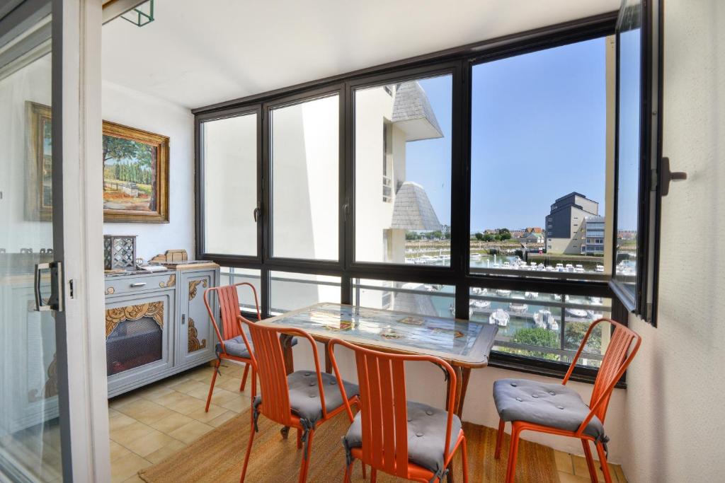 une salle à manger avec une table et des chaises et une fenêtre dans l'établissement Le Balcon sur Juno - A 10min à pied de la plage, à Courseulles-sur-Mer