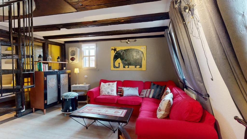 - un salon avec un canapé rouge et un éléphant sur le mur dans l'établissement La Grande Ourse, à Colmar
