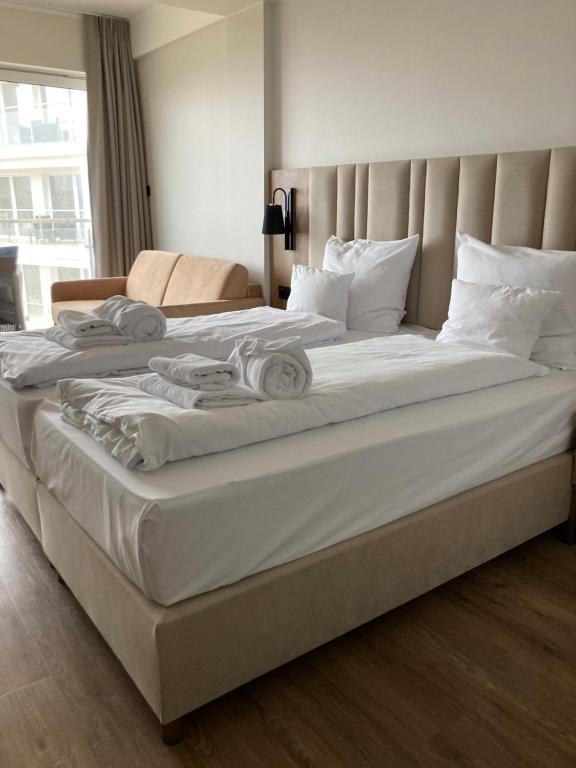 un grande letto con lenzuola bianche e cuscini sopra di Apartament Morski Widok a Jarosławiec