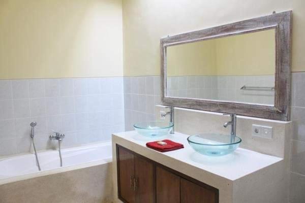a bathroom with two sinks and a mirror and a tub at Dana Villa Bali in Seminyak