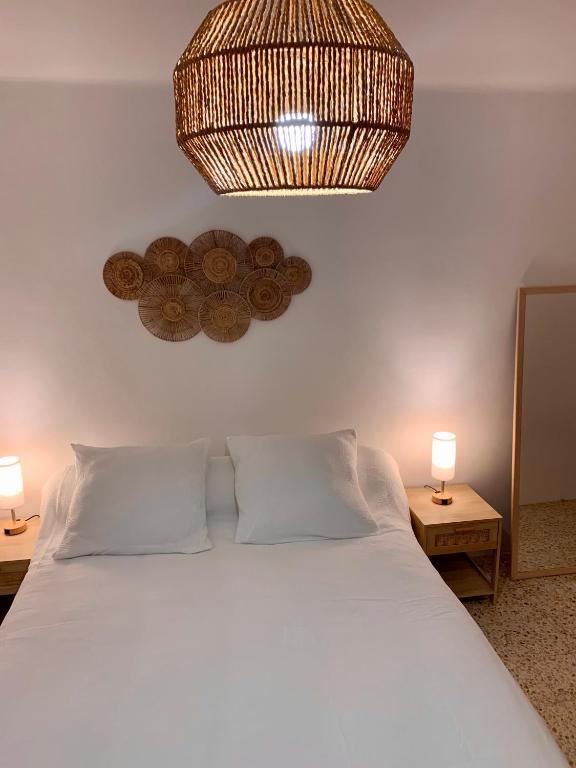 - une chambre avec un lit blanc et un lustre dans l'établissement T1 Sélizia, à Canet