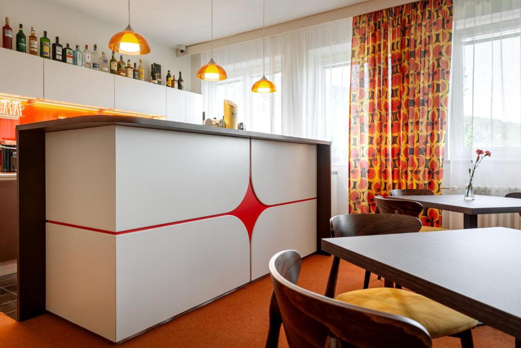 a restaurant with a counter and chairs and tables at Retro Hotel JISKRA in Čeladná