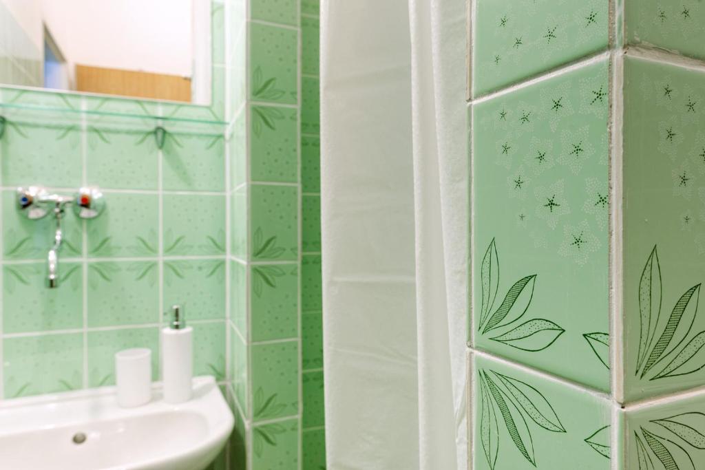a bathroom with green tiled walls and a sink at Retro Hotel JISKRA in Čeladná