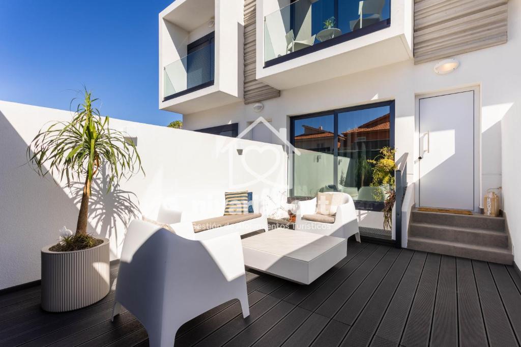 a patio with white furniture on a wooden deck at The Oasis El Medano, by Nivariahost in El Médano