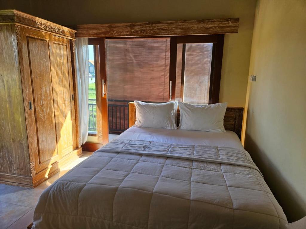 a large bed in a room with a window at KRISNA TAPAN GUEST HOUSE in Ubud