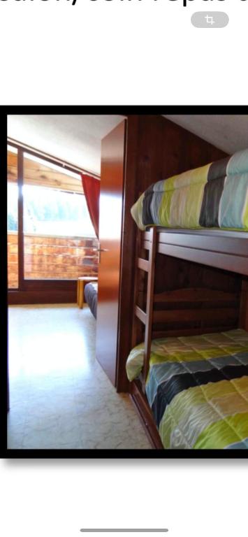 Ce lit superposé se trouve dans un dortoir doté d'une fenêtre. dans l'établissement Studio Montagne, à Taninges