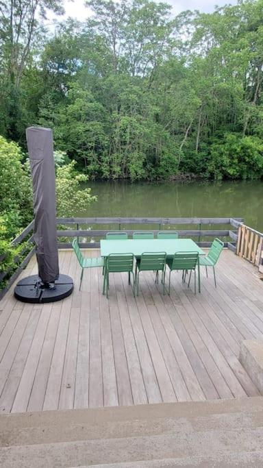 une table et des chaises sur une terrasse en bois avec une télévision dans l'établissement River house with 3 bedrooms, à Montigny-sur-Loing