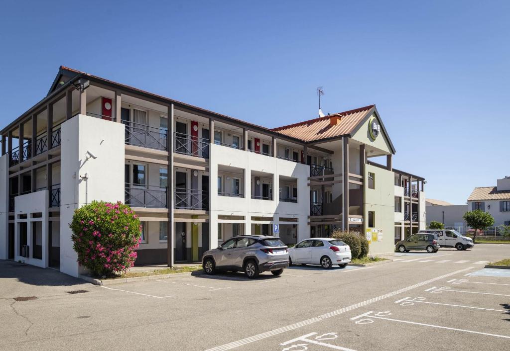 an apartment building with cars parked in a parking lot at B&B HOTEL Avignon 1 in Le Pontet