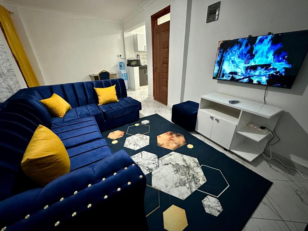 ナイロビにあるStelvic One Bedroom Airbnbの青いソファと薄型テレビのあるリビングルーム