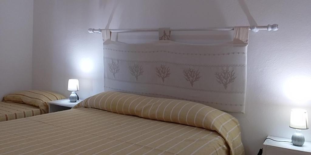 a bedroom with two beds and two lights on the wall at Casa Marconi in San Teodoro