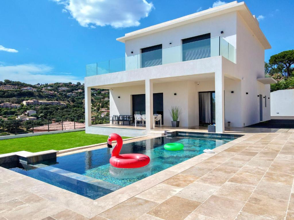 une maison avec une piscine avec un cygne rouge dedans dans l'établissement Villa du Golf, à Sainte-Maxime