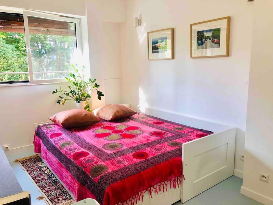 Cette chambre blanche comprend un lit avec une couverture rouge. dans l'établissement STUDIO, 11, parc de Belleville, à Paris