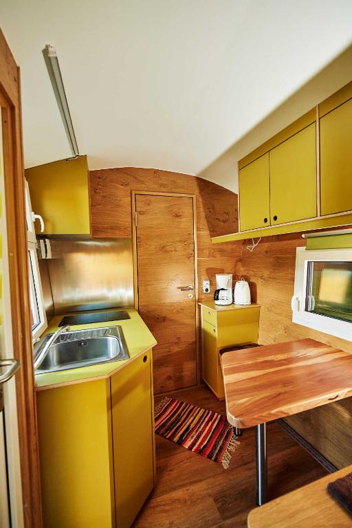 a small kitchen with yellow cabinets and a sink at Schäferwagen Skudde in Gräfenberg