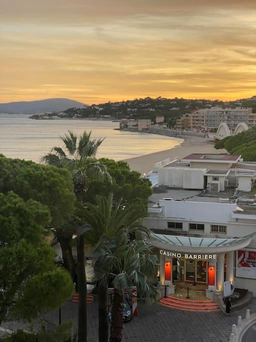 un bâtiment avec des palmiers en face d'une plage dans l'établissement Appartement plein centre, à Sainte-Maxime