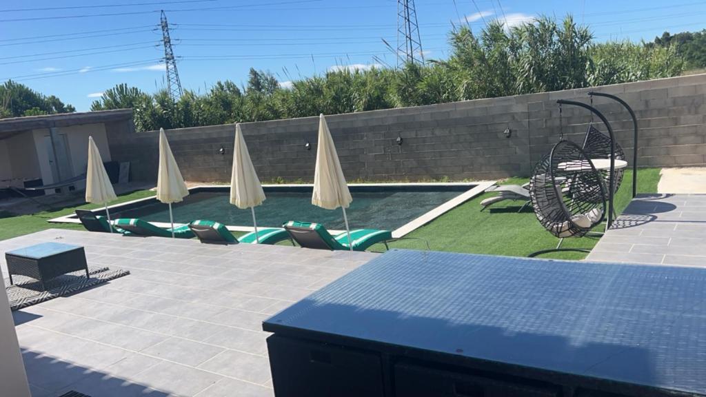 un patio avec des parasols et des chaises ainsi qu'une piscine dans l'établissement Villa avec piscine, à Narbonne