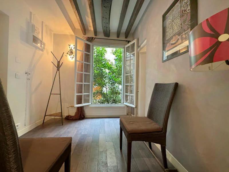 un salon avec une chaise et une fenêtre dans l'établissement Notre-Dame - Studio, à Paris