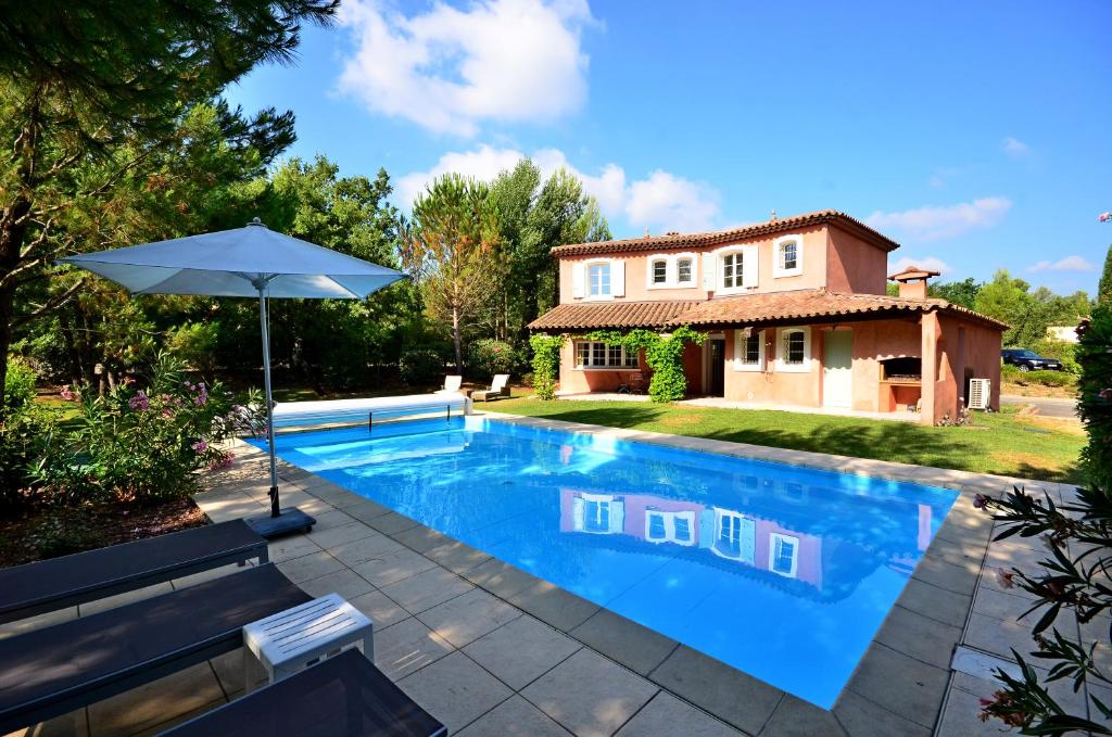 a pool in front of a house with an umbrella at Villa Les Mimosas, Fayence in Fayence