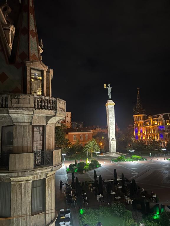 een uitzicht op een stad in de nacht met een standbeeld bij Rooms on Europe Square in Batoemi