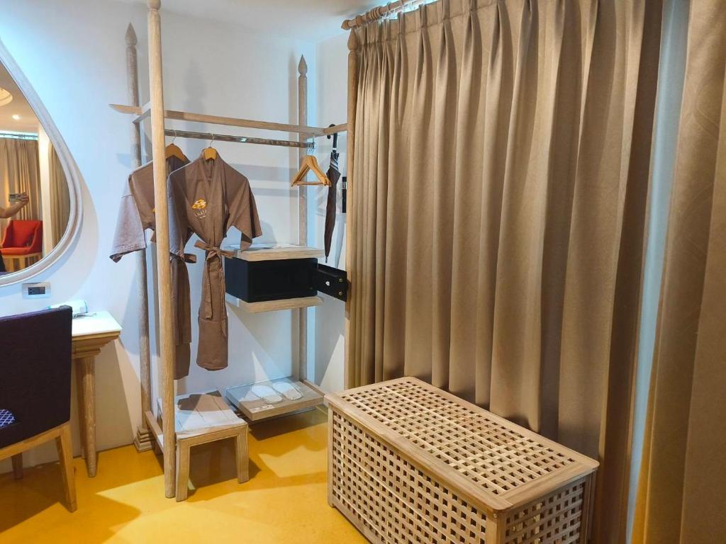 An open dressing area with hanging garments, shelves, a safe, mirror and curtained partition.