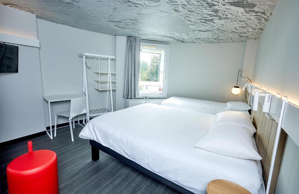 une chambre avec un lit blanc et un bureau dans l'établissement ibis Auxerre Centre, à Auxerre