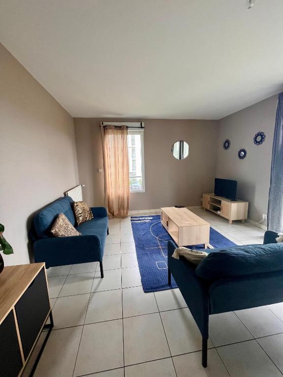un salon avec deux canapés bleus et une table dans l'établissement Appartement rénové avec grande terrasse, à Cesson-Sévigné