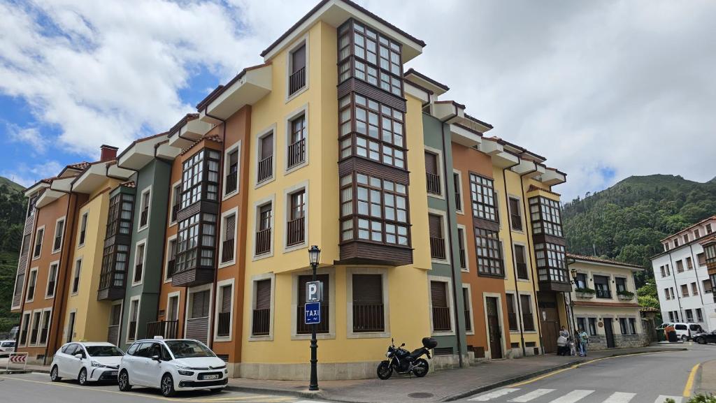 a yellow building with cars parked in front of it at Apartamento Cuevas de Mar in Cuevas