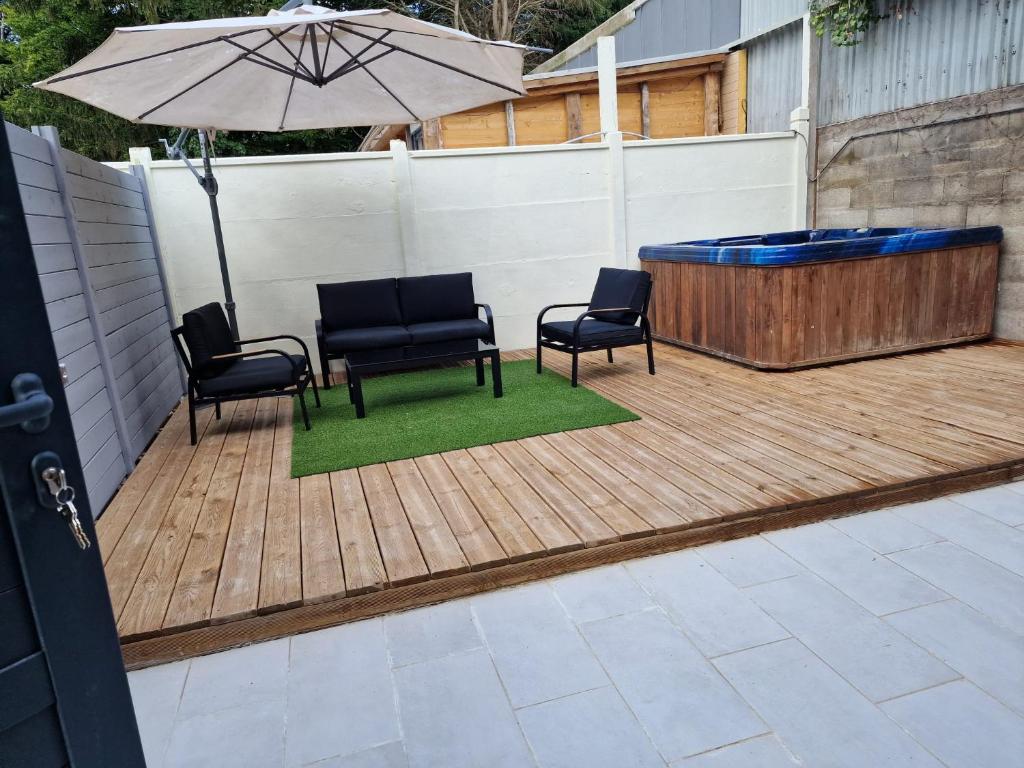 un patio avec trois chaises et un parasol et un bain à remous dans l'établissement Maison familiale, à Pierrefitte-sur-Seine