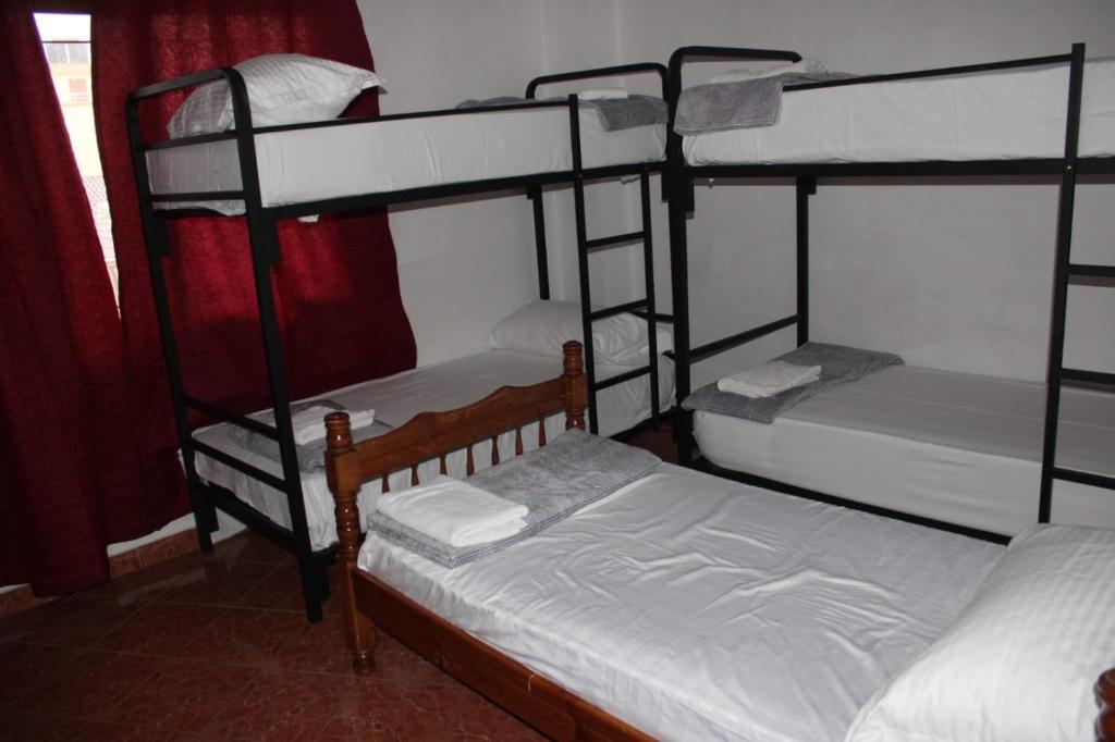 a bedroom with three bunk beds with white sheets at Crew Hostel Tirana in Tirana