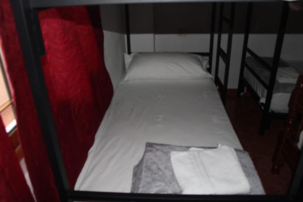 two beds in a small room with white sheets at Crew Hostel Tirana in Tirana